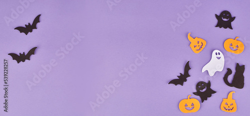 Halloween decorations, pumpkins, on violet background. Halloween party greeting card. Copy space. Flat lay, top view, overhead.