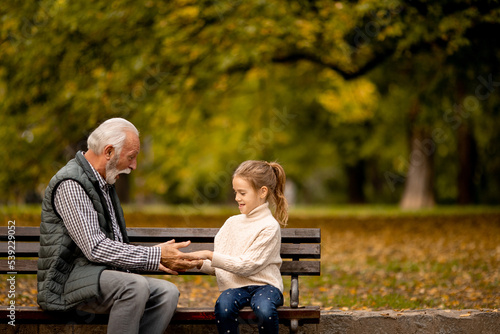 Grandfather playing red hands slapping game with his granddaughter in park on autumn day © BGStock72