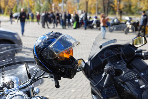 Closeup black moto helmet on motorcycle handlebars against blurred background