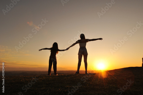 mãe e filha de mãos dadas em por do sol 