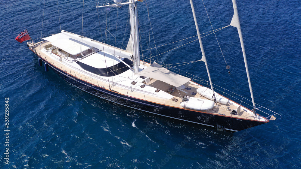 Aerial drone photo of beautiful sail boat anchored in deep blue open ocean sea Aerial drone photo of beautiful sail boat anchored in deep blue open ocean sea