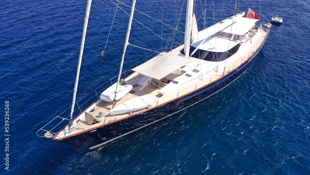 Aerial drone top down photo of beautiful sailing boat anchored in deep blue sea of Mykonos island, Cyclades, Greece Aerial drone top down photo of beautiful sailing boat anchored in deep blue sea of Mykonos island, Cyclades, Greece