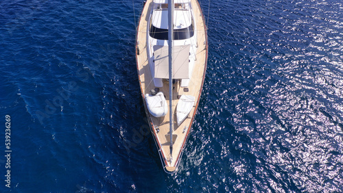 Aerial drone top down photo of beautiful sailing boat anchored in deep blue sea of Mykonos island, Cyclades, Greece © aerial-drone