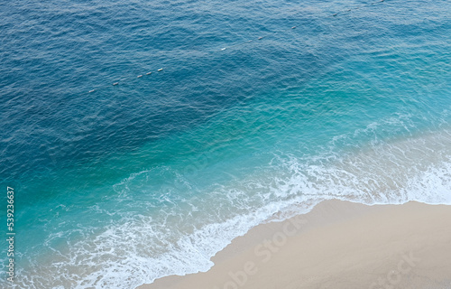 Turquoise sea holiday concept from above. Empty beach from above with sea and sand. Holiday background with turquoise sea and sand. Open space area.