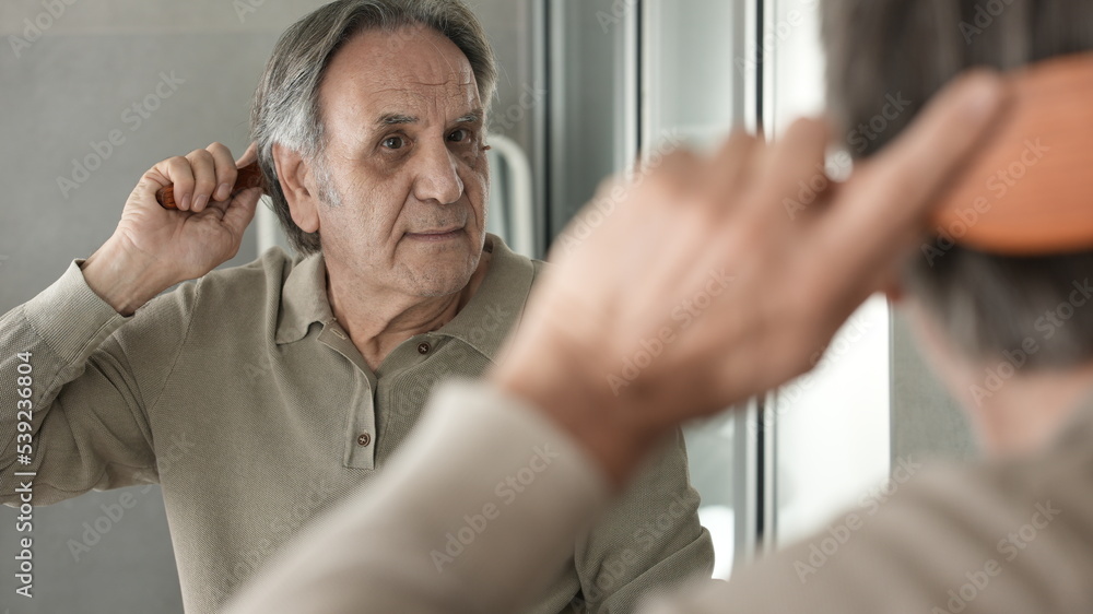 Senior man combing his hair in the bathroom Senior man combing his hair in the bathroom