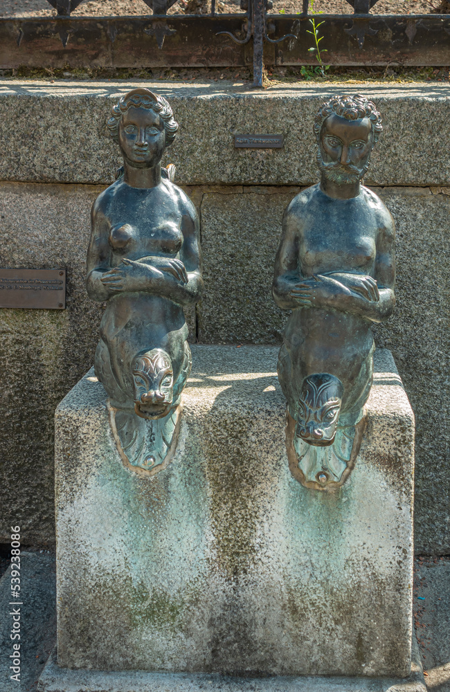 Germany, Wismar - July 13, 2022: Closeup of Nix und Nixe statues on Wasserkunst, Duch renaissance monument built on top of natural water source. Faucets are dry here. - obrazy, fototapety, plakaty 