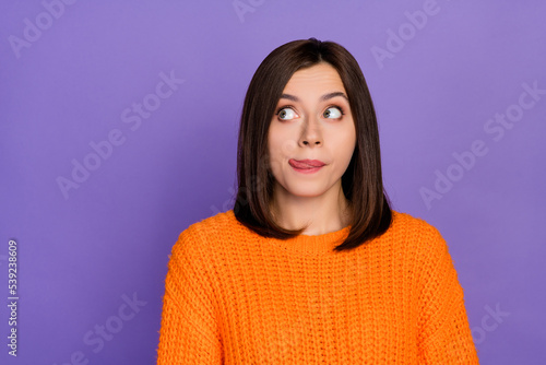 Photo portrait of gorgeous young woman look empty space lick lips dressed stylish knitted orange outfit isolated on purple color background