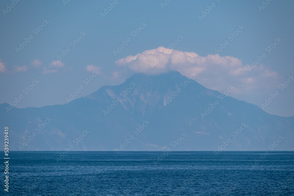 Panoramic early morning view of cloud covered holy Mount Athos from Fava sand beach, Vourvourou, peninsula Sithonia, Chalkidiki (Halkidiki), Greece, Europe. Summer vacation at Aegean Mediterranean Sea