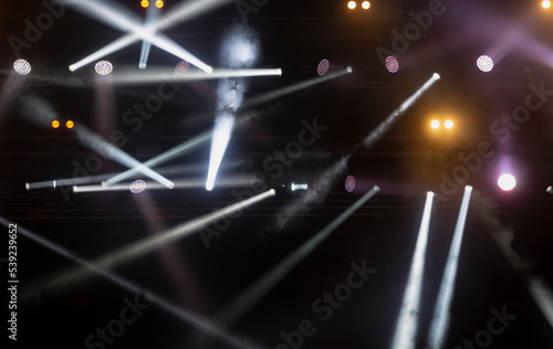 Stage lighting. Spotlights with colored lights on a stage. Artificial lighting. Black background and blur.