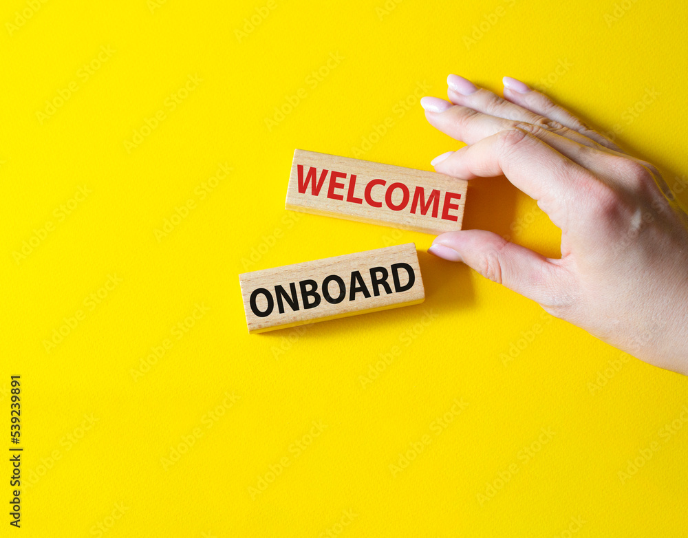 Welcome onboard symbol. Concept words Welcome onboard on wooden blocks. Beautiful yellow background. Businessman hand. Business and Welcome onboard concept. Copy space. Welcome onboard symbol. Concept words Welcome onboard on wooden blocks. Beautiful yellow background. Businessman hand. Business and Welcome onboard concept. Copy space.
