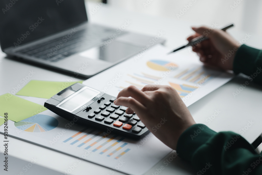 Business woman using a calculator to calculate numbers on a company's financial documents, she is analyzing historical financial data to plan how to grow the company. Financial concept.