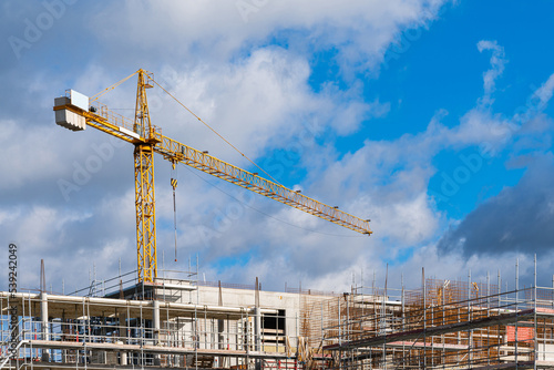 Tower crane over building under construction in scaffolding. © Viktor