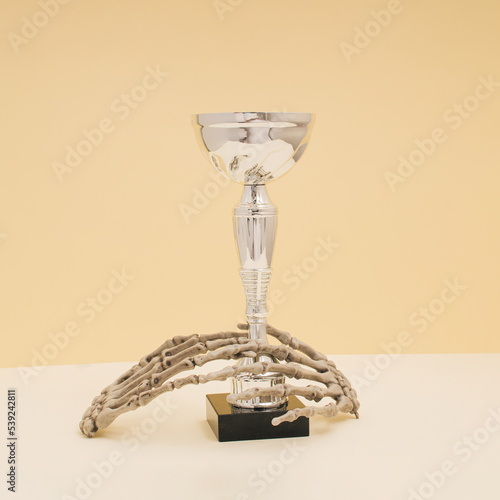 Silver trophy or award cup with skeleton hands. Concept of posthumous awards. photo