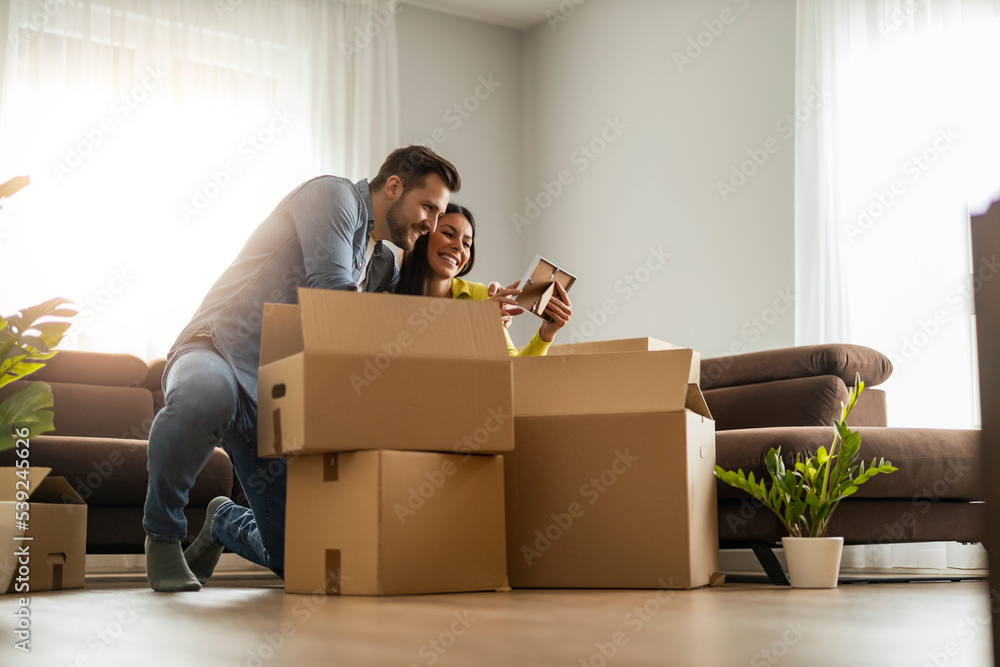 Smiling couple unpaking boxes in new home Smiling couple unpaking boxes in new home