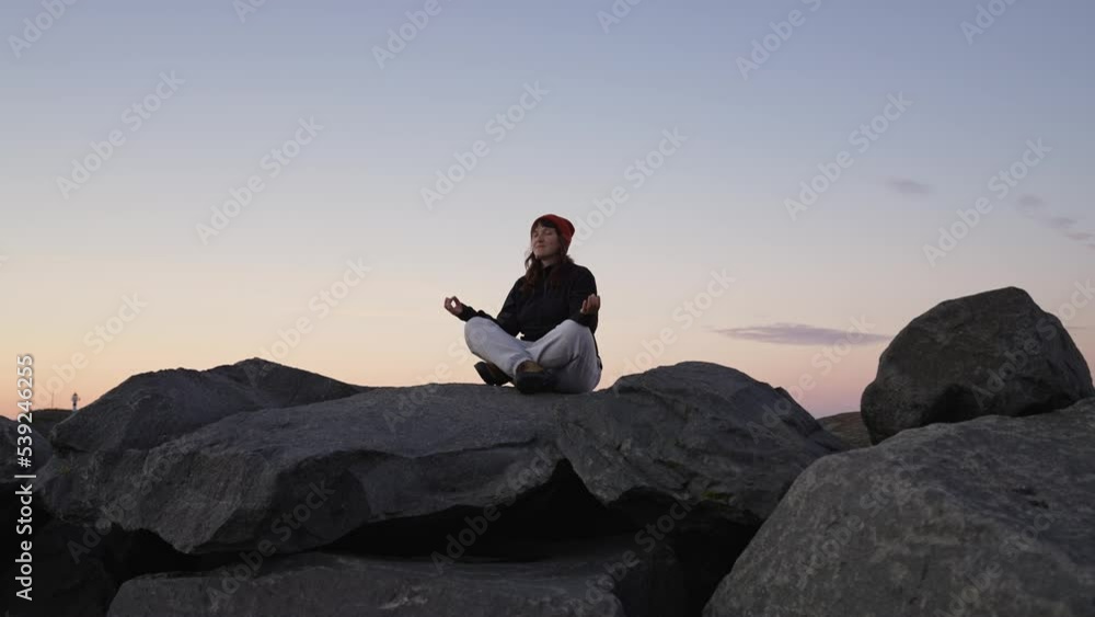 travel girl sits on a big stone and looks at the sea. theme of inner peace and relaxation