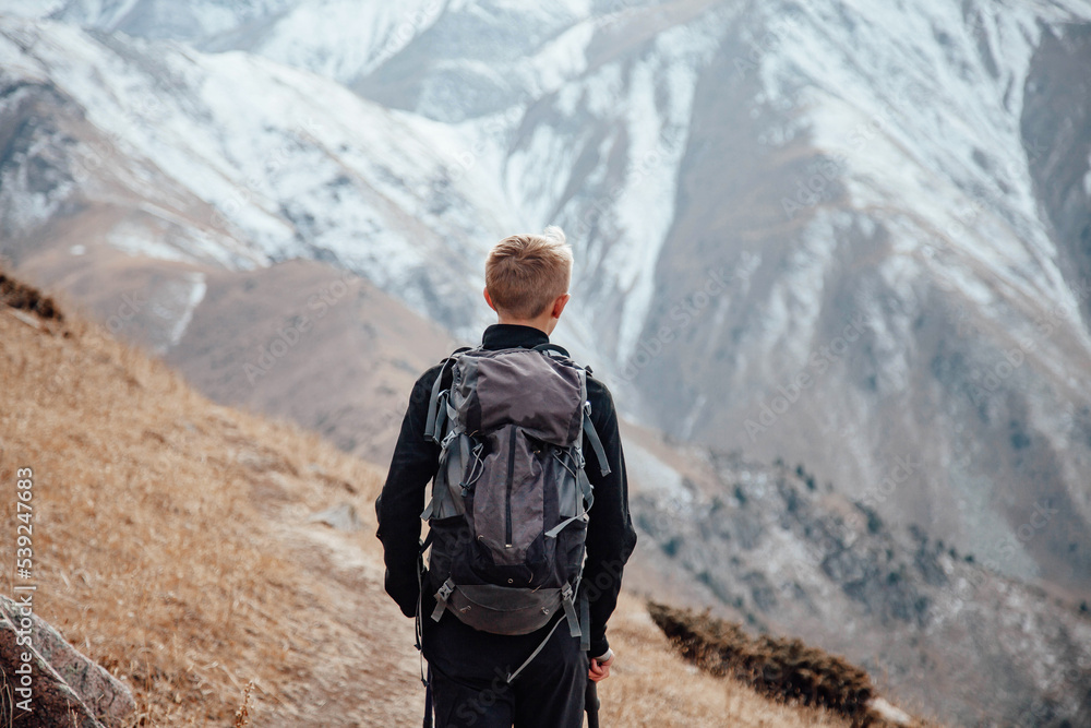 Young traveler with a backpack on the road enjoying view of the mountains.