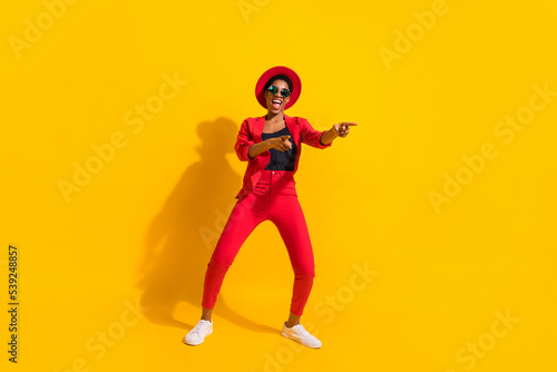 Photo of attractive funky short hair human wear formal outfit cap eyewear dancing pointing empty space isolated yellow color background
