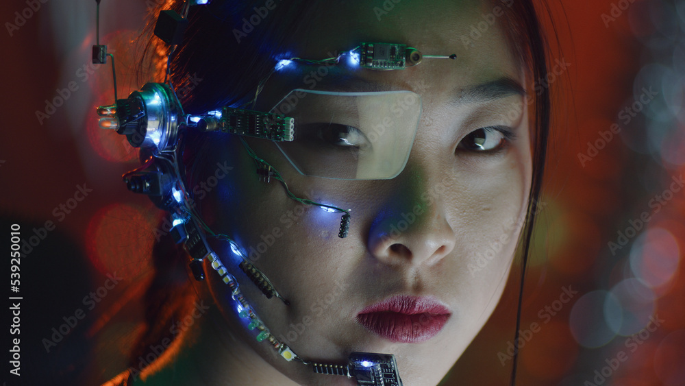 A Cyberpunk girl wearing a headset with microphone, one-eye glasses and  white small LED lights. Red neon lights in the background. Asian girl in  cyberpunk attire. Cyber and sci-fi backgrounds. Photos
