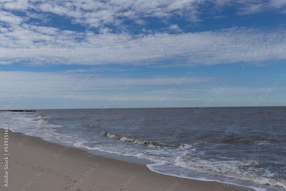The ocean is beating the shore here. There was a hurricane off the coast at the time that produced some rough waves. I love the blue sky with patched of clouds. This was at Cape May New Jersey.