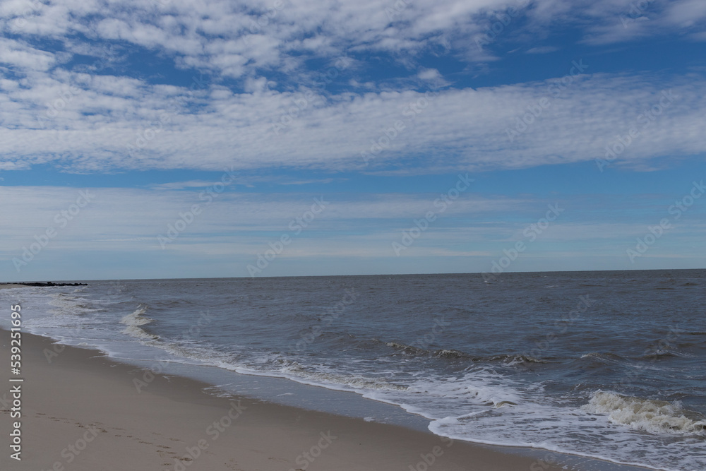 The ocean is beating the shore here. There was a hurricane off the coast at the time that produced some rough waves. I love the blue sky with patched of clouds. This was at Cape May New Jersey. The ocean is beating the shore here. There was a hurricane off the coast at the time that produced some rough waves. I love the blue sky with patched of clouds. This was at Cape May New Jersey.