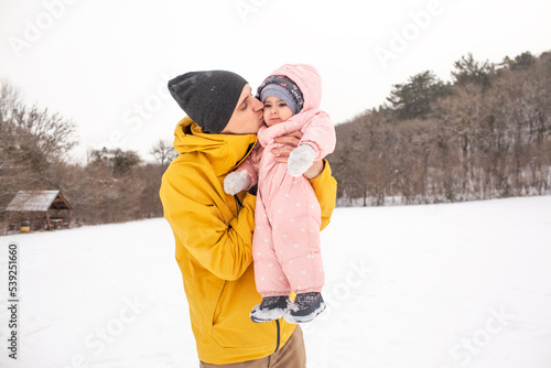 Happy father play and have fun woth baby. Man holding the female toddler in the hands and laughing on a cold winter day