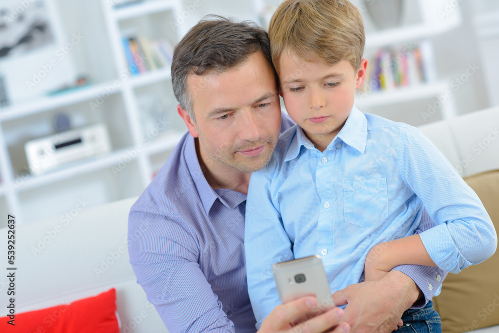 Adult and child looking at cellphone Adult and child looking at cellphone