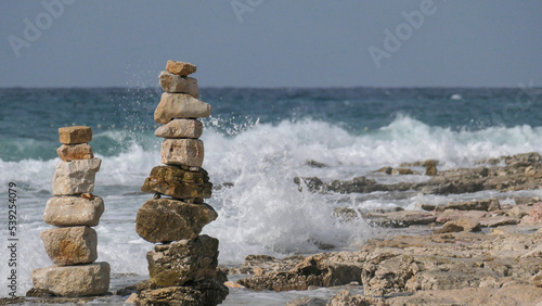 Piled up stones on the coast of the sea. Background wild waves breaking on the beach.