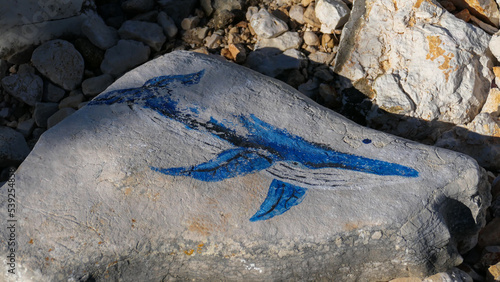 Drawing of a whale on a stone by the sea