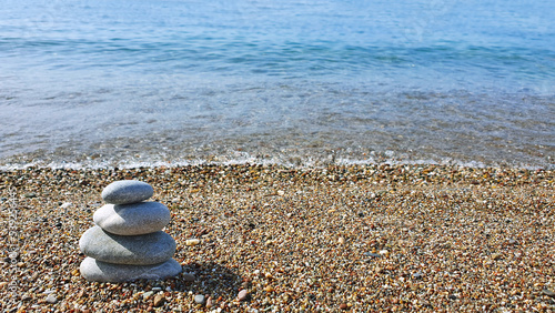 Spa stones balance on the sand of the beach.