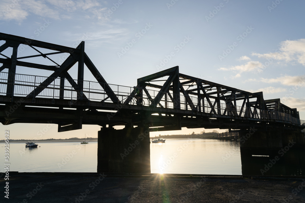 Fototapeta premium Sunrise glows through Tauranga Railway bridge silhouette