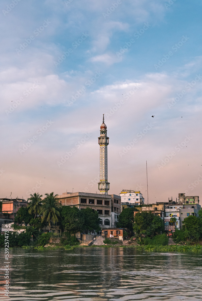 The locality has developed along the banks of the river. A mosque with a tall tower stands in the middle of it.