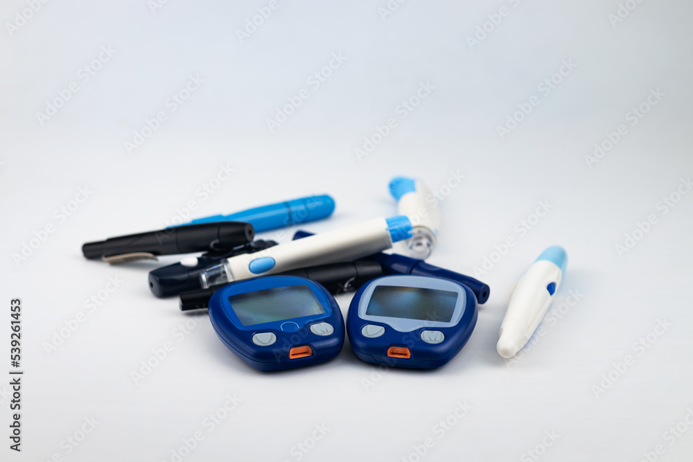 Glucose meter, lancets, insulin syringe pens on a white background