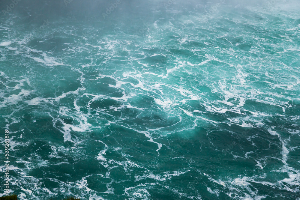 Defocused water background - whirlpool waves, blue tint. Abstract background with liquid fluid texture. Niagara river Defocused water background - whirlpool waves, blue tint. Abstract background with liquid fluid texture. Niagara river