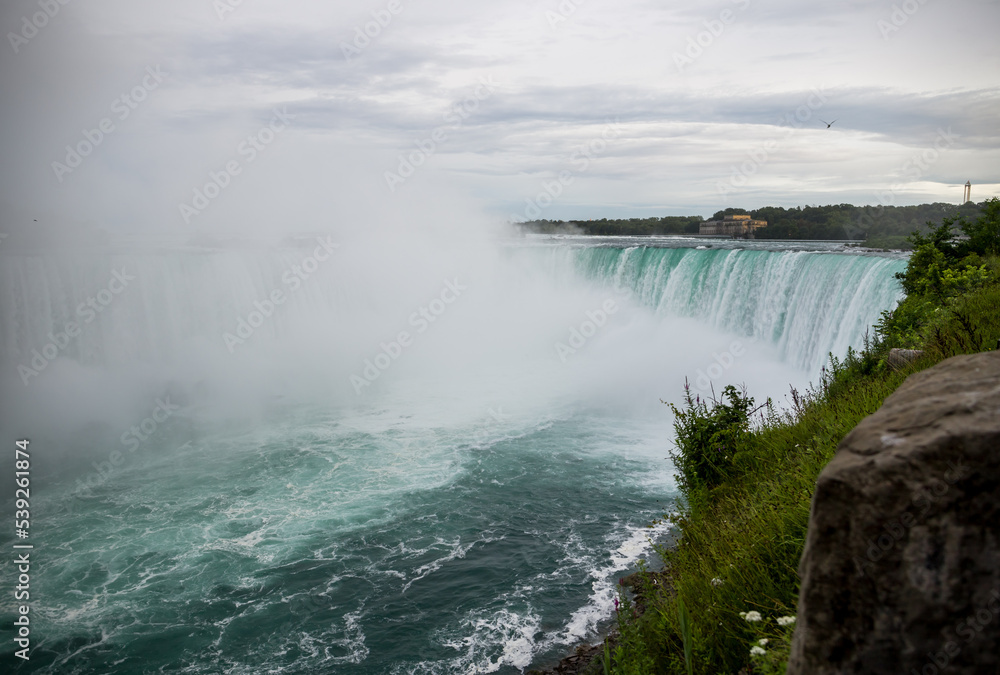 Niagara Horseshoe falls on sunset - blue water, haze and cloudy sky. Dramatic tones Niagara Horseshoe falls on sunset - blue water, haze and cloudy sky. Dramatic tones