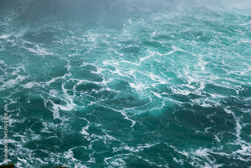 Defocused water background - whirlpool waves, blue tint. Abstract background with liquid fluid texture. Niagara river 