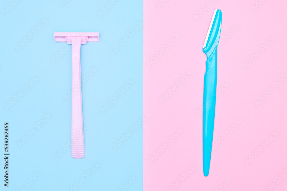 Two disposable razor blades of different colors for removing, shaving unwanted hair on face and body on blue and pink background