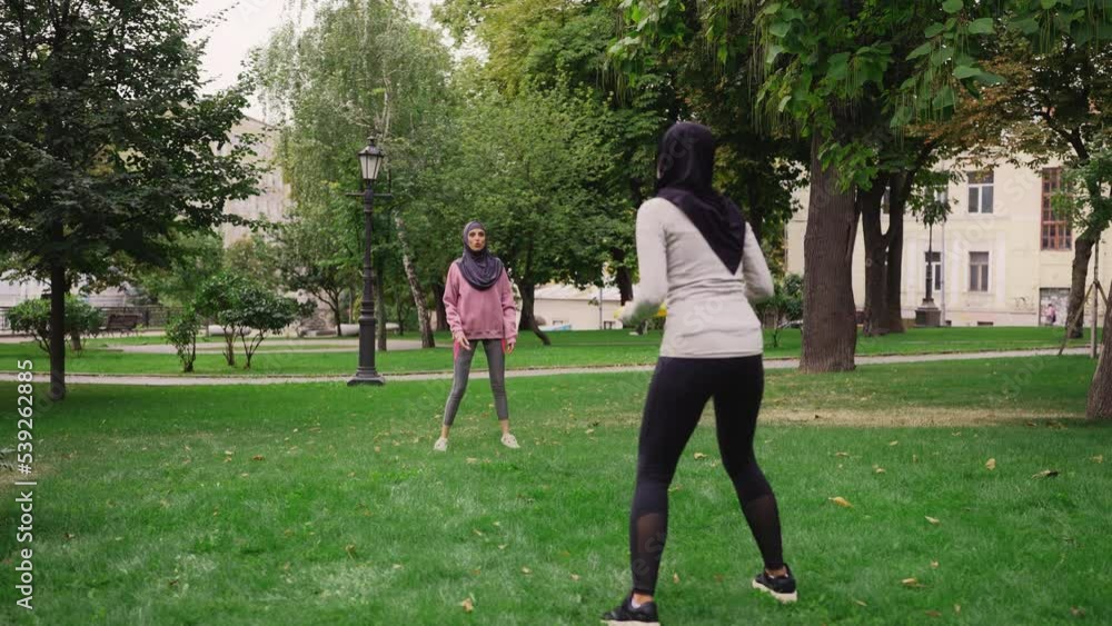 Arab women in hijabs throwing flying disc, training partners, healthy activity Arab women in hijabs throwing flying disc, training partners, healthy activity