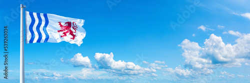 Nouvelle-Aquitaine, France - flag waving on a blue sky in beautiful clouds - Horizontal banner