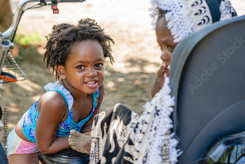 Imagen horizontal de una niña afroamericana junto a su pequeño hermano al aire libre en un hermoso día de verano.  photo