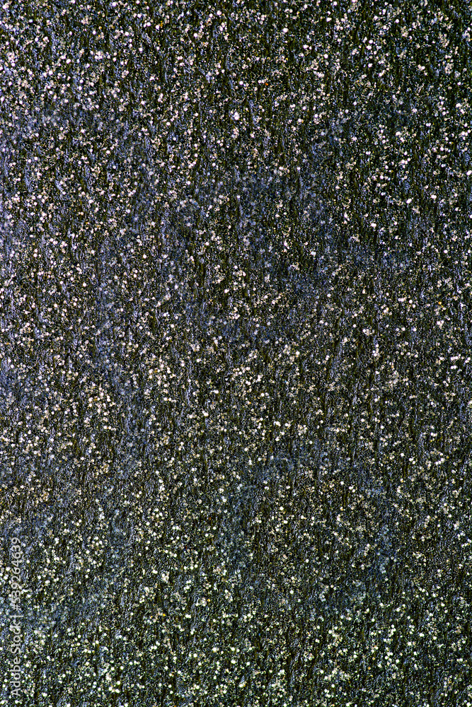 Shiny gold sequins on a rough surface of dark color Shiny gold sequins on a rough surface of dark color