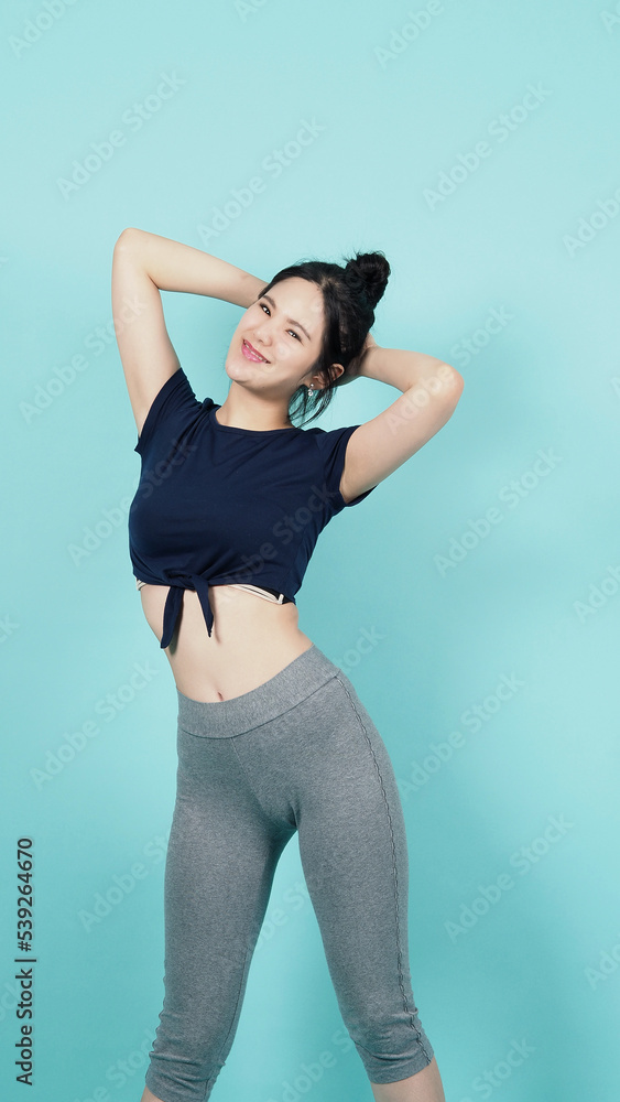 Obraz premium Fitness sportswear woman smile and pose body exercise at camera isolated on blue green background. Perfect body sporty woman relaxing after training. Fit and firm people. Sport Health and wellness.