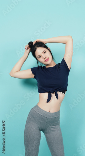 Fitness sportswear woman smile and pose body exercise at camera isolated on blue green background. Perfect body sporty woman relaxing after training. Fit and firm people. Sport Health and wellness.