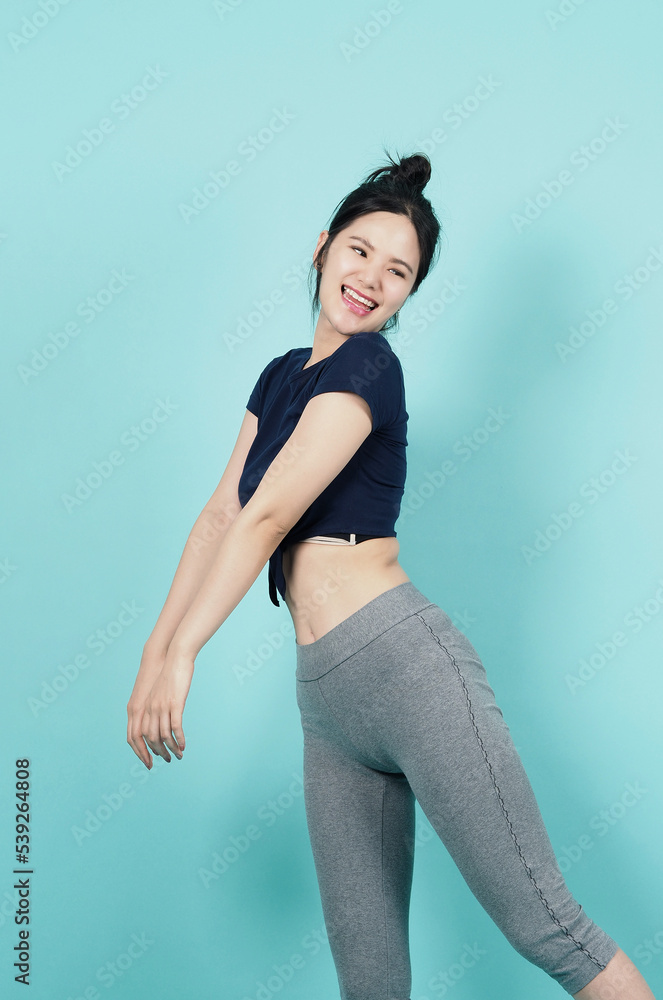 Fitness sportswear woman smile and pose body exercise at camera isolated on blue green background. Perfect body sporty woman relaxing after training. Fit and firm people. Sport Health and wellness. Fitness sportswear woman smile and pose body exercise at camera isolated on blue green background. Perfect body sporty woman relaxing after training. Fit and firm people. Sport Health and wellness.