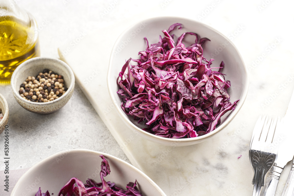 Two salad bowls with german red cabbage chopped in fine stripes on marble board on grey background Two salad bowls with german red cabbage chopped in fine stripes on marble board on grey background