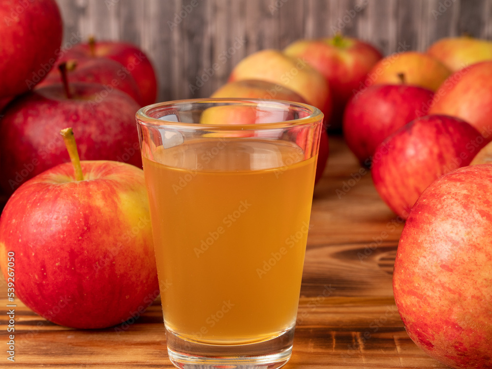 Apple cider vinegar in a glass with apples on a wooden background. Apple cider vinegar in a glass with apples on a wooden background.