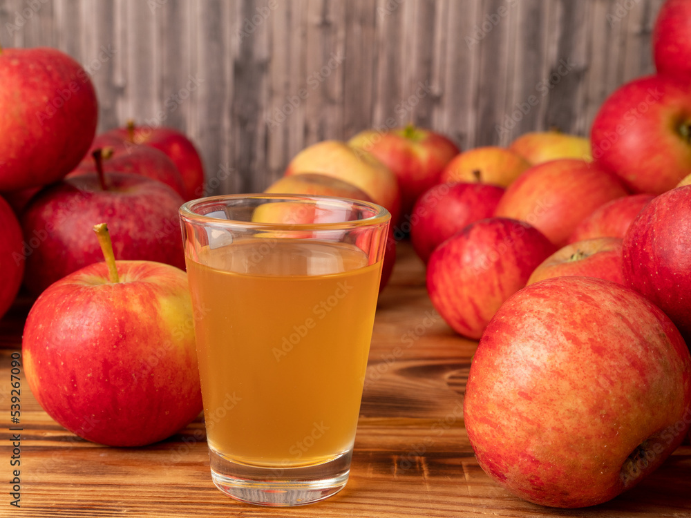 Apple cider vinegar in a glass with apples on a wooden background. Apple cider vinegar in a glass with apples on a wooden background.