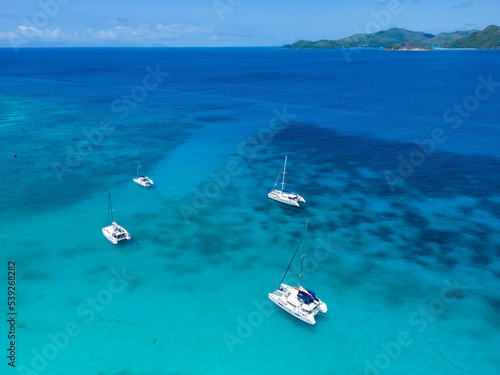 Aerial drone of luxury yachts anchored in tropical exotic island with crystal clear turquoise sea and 