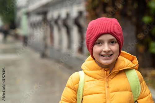 portrait of a happy schoolboy in a jacket with a backpack going to school in autumn