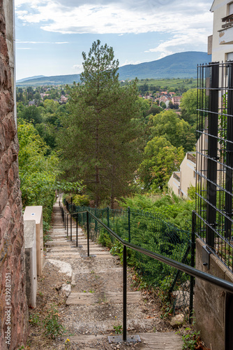 Obernai, France - 09 05 2022: View of an uphill street with steps to join terraced vines and the National Memorial of Forced Incorporated