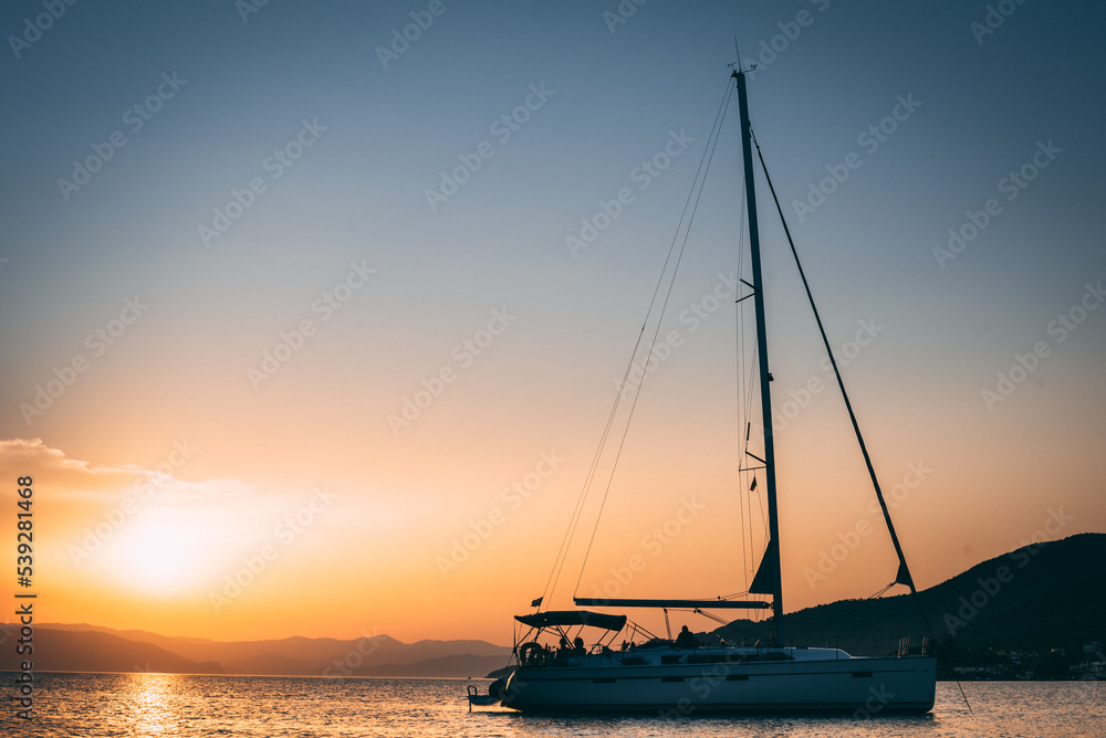 A serene sailboat gon calm waters, framed by a sky of sunset hues. Its elegance and stillness evoke timeless maritime allure.